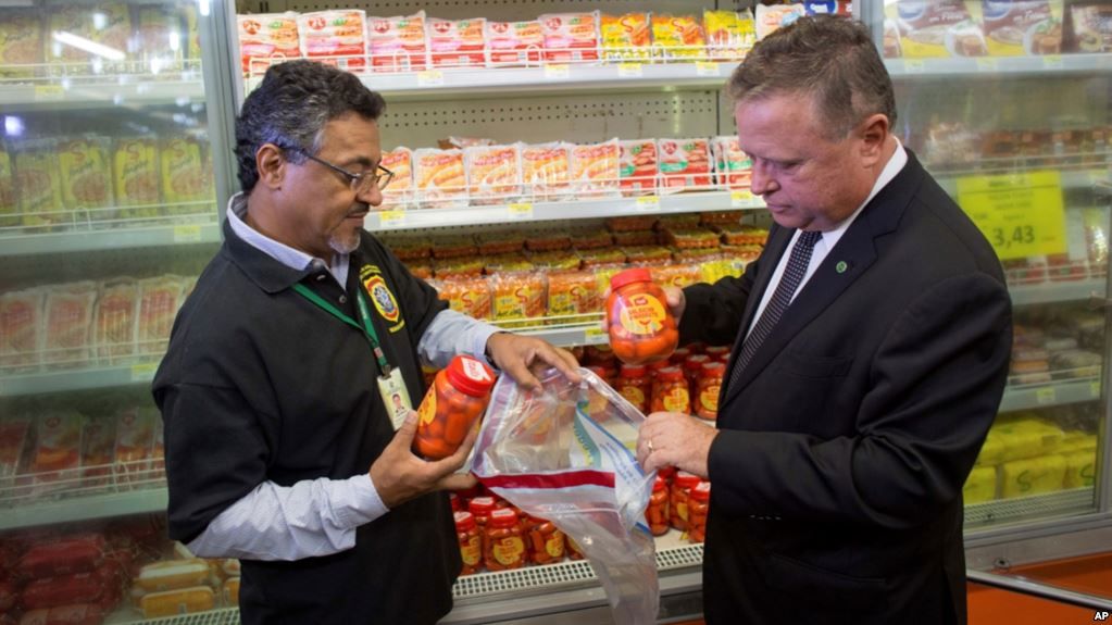 El ministro de Agricultura de Brasil, Blairo Maggi, acompañado por un agente de inspección sanitaria, recolecta productos de carne para pruebas, en un supermercado de Brasilia.