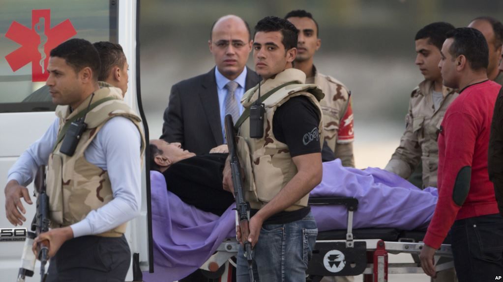El depuesto presidente egipcio Hosni Mubarak es esoltado por personal médico y de seguridad hacia una ambulancia en el hospital militar Maadi en El Cairo, Egipto, el 2 de marzo, de 2017.
