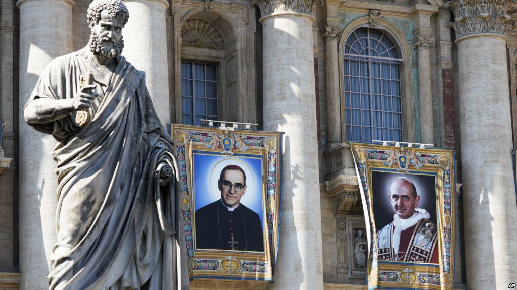 Tapices del arzobispo católico Oscar Romero, a la izquierda, y el Papa Paulo VI cuelgan de un balcón de la fachada de la Basílica de San Pedro en el Vaticano, 13 de octubre de 2018.